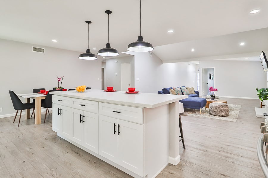 its open-concept design featuring a sleek white kitchen island with MSI Quartz countertops, stylish dining area, and inviting living room, ideal for a memorable stay.