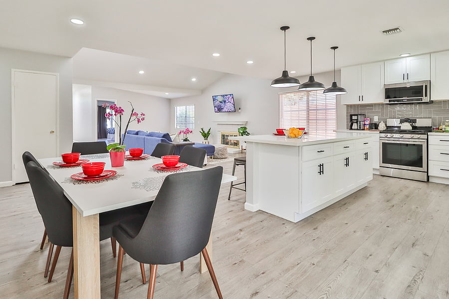 Discover the seamless flow of this where a modern white kitchen with a central island connects to a stylish dining area and a comfortable living room, creating an ideal space for relaxation and entertaining.