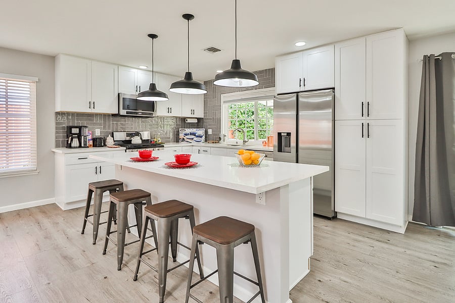 spacious kitchen island, featuring modern white cabinetry, stainless steel appliances, and stylish pendant lighting, perfect for a comfortable and convenient stay.