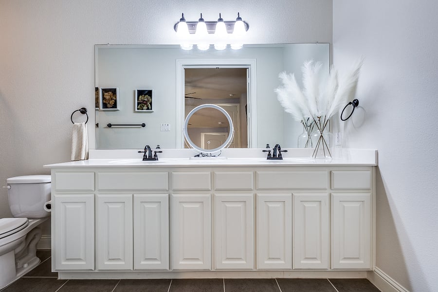 Private full bathroom with tile floor, 2 vanity double sinks, laundry hamper and make up mirror. Toilet, large mirror, and plenty of cabinet space that contains hair dryer, towels, toilet paper, portable fan, basic toiletries, and other essentials.