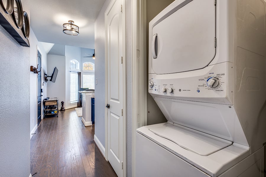 General Electric (GE) electric stacked laundry washer & dryer. Hallway closet with hangers & storage including extra bedding, sheets, blankets, comforter, linens, pillows, vacuum, broom, iron/board, detergent, step stool & portable fans/heaters.