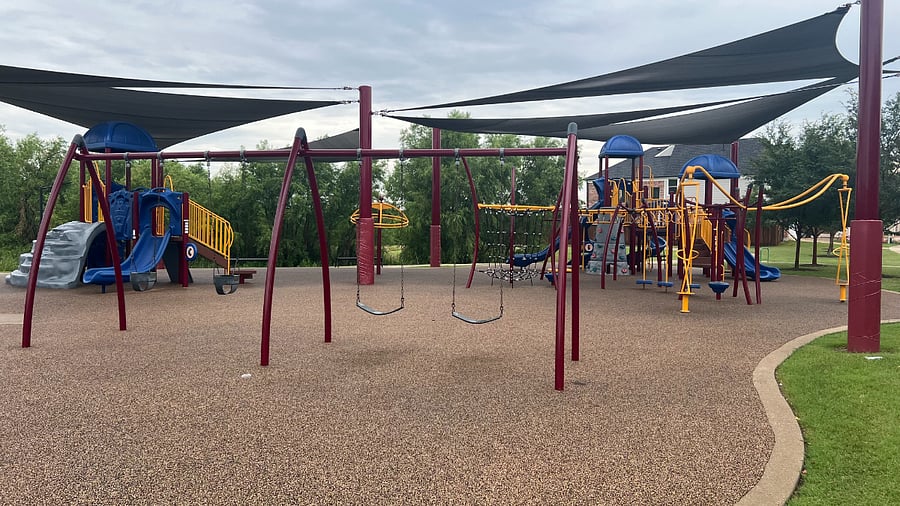 Frisco Hills community park playground with swings, slides, monkey bars, climbing wall, climbing net, and more!