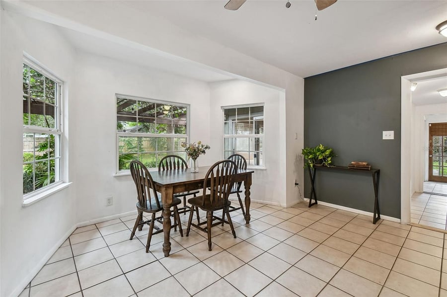 Bright dining area features triple window views of lush landscaping and covered pergola. Perfect setting for casual meals or entertaining, with easy access to kitchen and outdoor spaces.