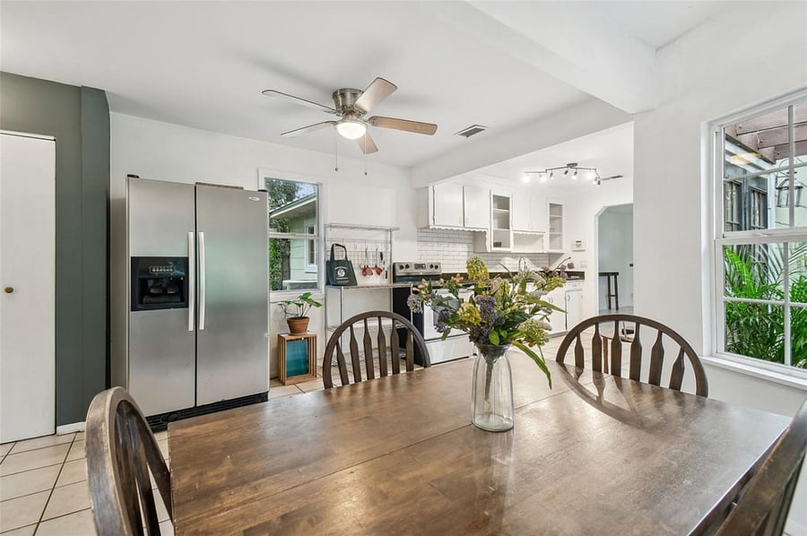 Bright dining area features triple window views of lush landscaping and covered pergola. Perfect setting for casual meals or entertaining, with easy access to kitchen and outdoor spaces.