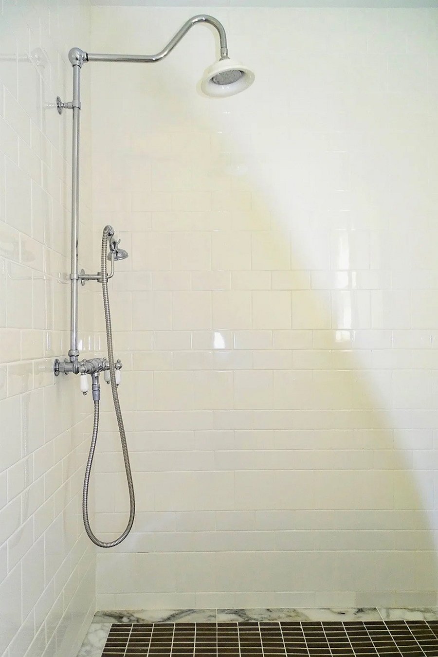 Walk-in shower with hand-held and overhead showerhead combination.