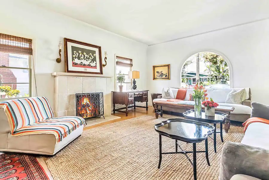 Bright and spacious living room with an arched picture window and wood burning fireplace - in main house