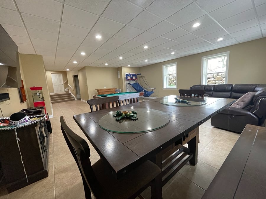 Basement/entertainment room with heated floors, pool table, pop-a-shot game, and large dining table.