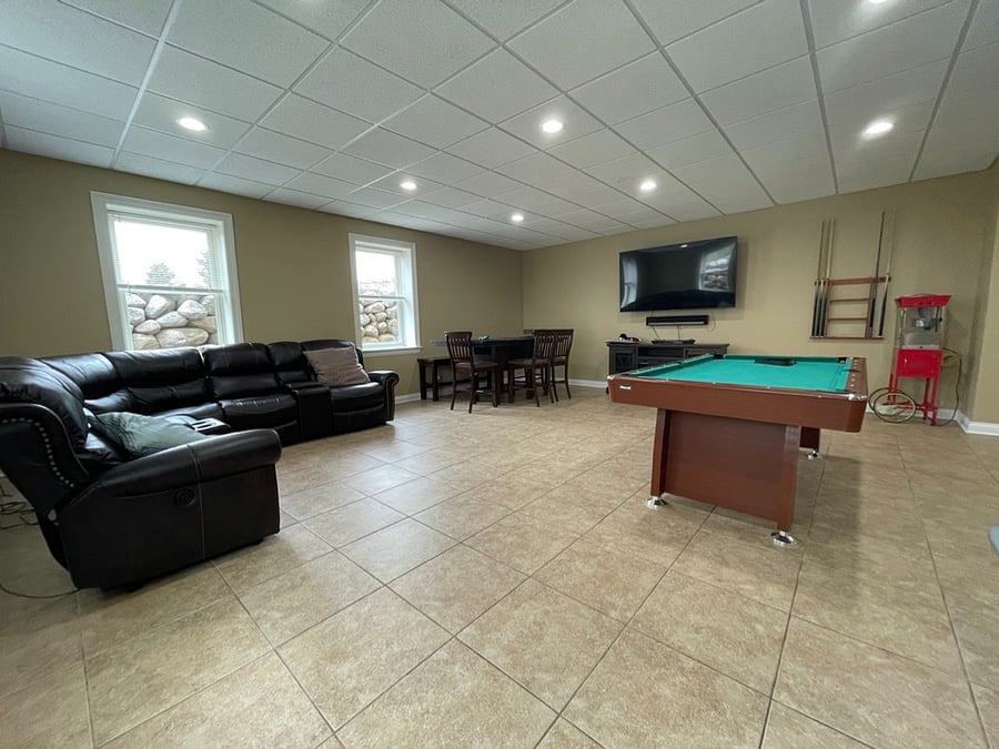 Large basement/entertainment room with pool table, lounge area, and 70" TV.