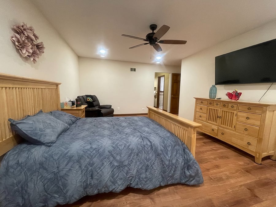 Master bedroom with queen size bed, television, and recliner. Bedroom has a walk in closet and en suite.