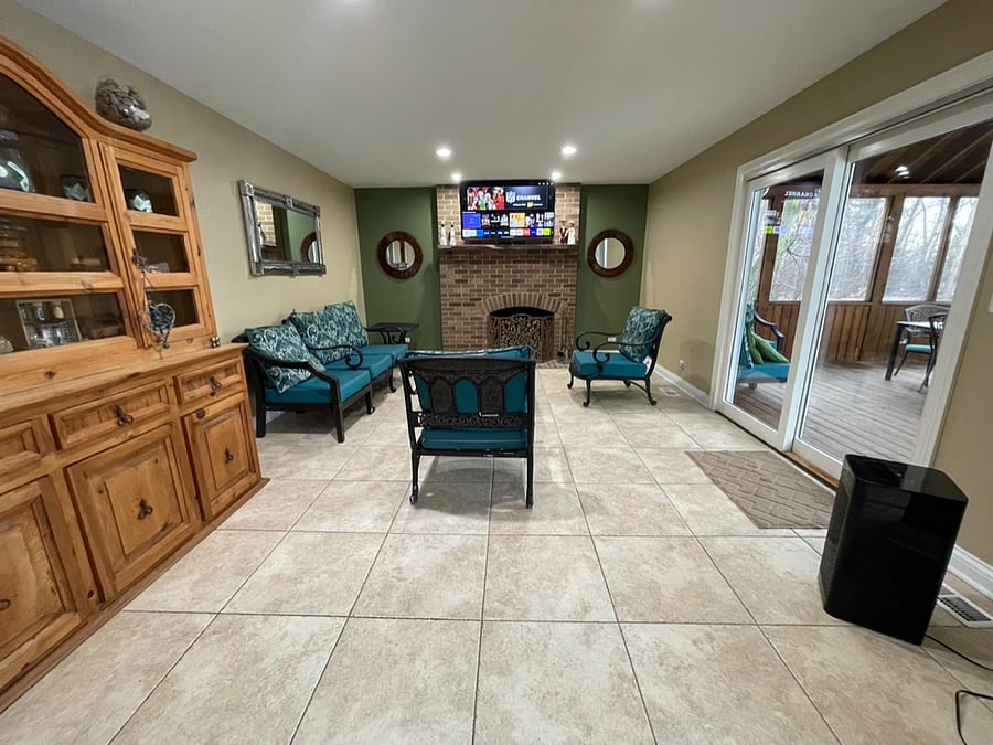 Living room with fireplace (decor only) and TV. This opens up to the sunroom.