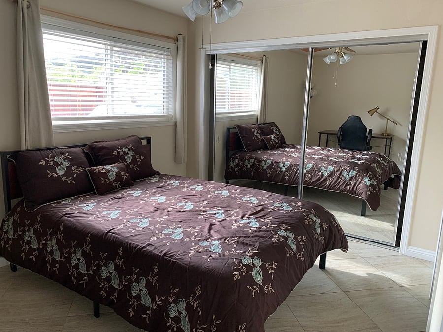Master Bedroom - queen size bed, workspace including desk, lamp, and ergonomic chair, floor to ceiling mirrors, tile floor and black-out curtains