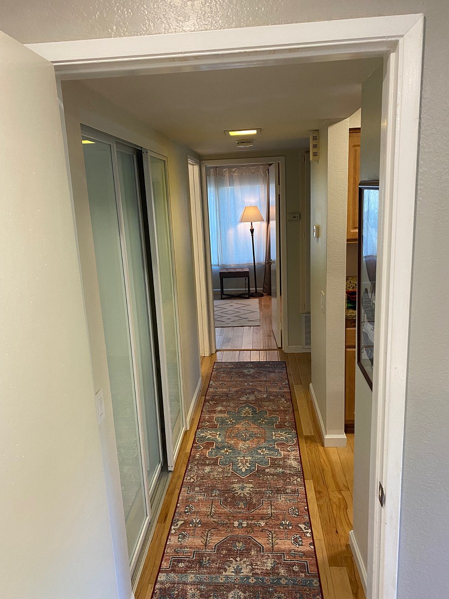 Long hallway between bedrooms. The kitchen is on the right. Large pantry on left with washer and dryer. It also contains accessories for the kitchen such as blender, air fryer, and Nespresso machine.