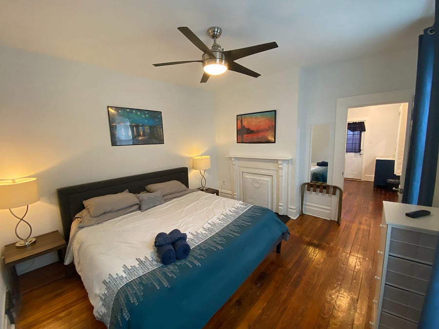 Main bedroom with comfortable king bed and captive bathroom, featuring a walk-in rainshower with exposed brick wall!