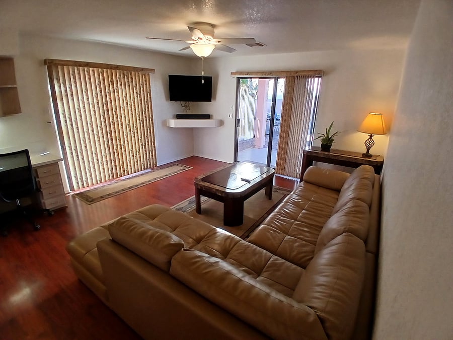 Living area with private patio to the right and pool access to the left. Electric roll-down security shutters cover both these sliding doors completely for complete privacy.