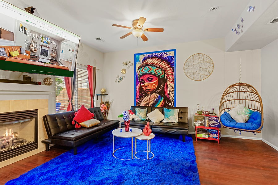 Spacious and eclectic living room with a cozy fireplace, comfortable seating, and a unique hanging chair. Perfect for relaxing and unwinding.
