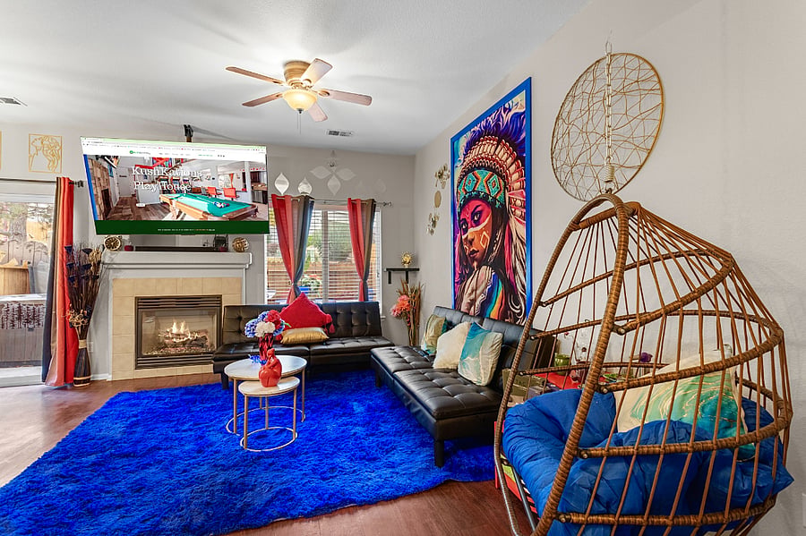 Spacious and eclectic living room with a cozy fireplace, comfortable seating, and a unique hanging chair. Perfect for relaxing and unwinding.