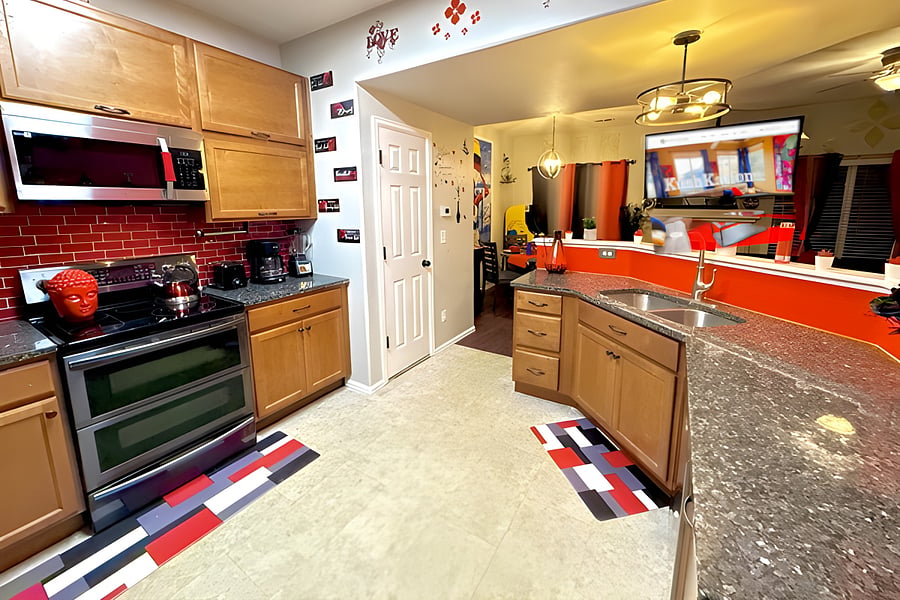 This cozy kitchen features a bold red and black theme with warm cabinetry and artistic, welcoming decor.