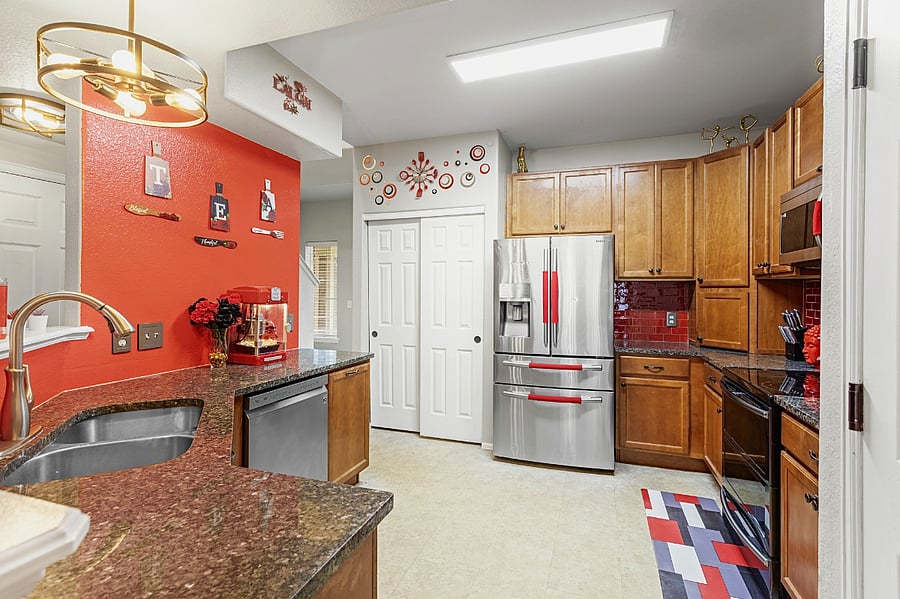 Spacious and well-equipped kitchen with modern appliances and a stylish red accent wall. Perfect for cooking up a feast or enjoying a quick meal.