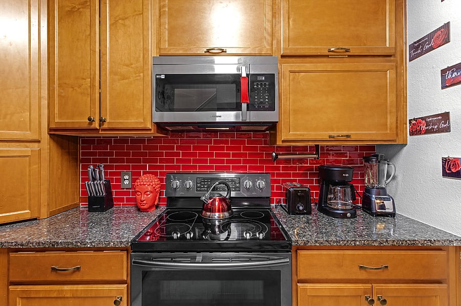 Well-equipped kitchen with modern appliances and a stylish red tile backsplash. Perfect for whipping up a delicious meal.