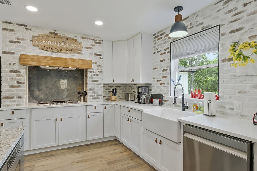 A large custom chef's kitchen with a barn door pantry, gas stove top, drawer-style microwave in the island, double oven, and farm-style sink.