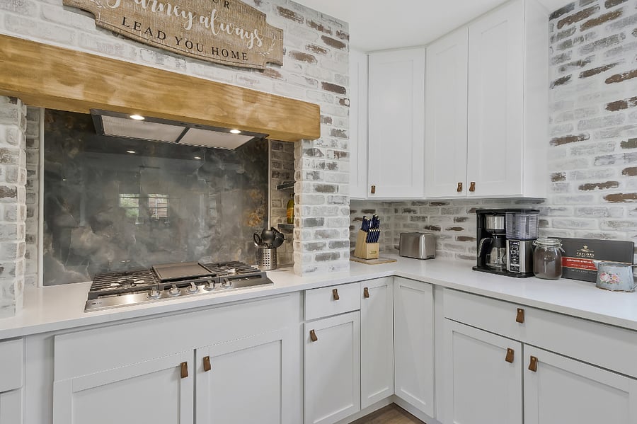 A large custom chef's kitchen with a barn door pantry, gas stove top, drawer-style microwave in the island, double oven, and farm-style sink.