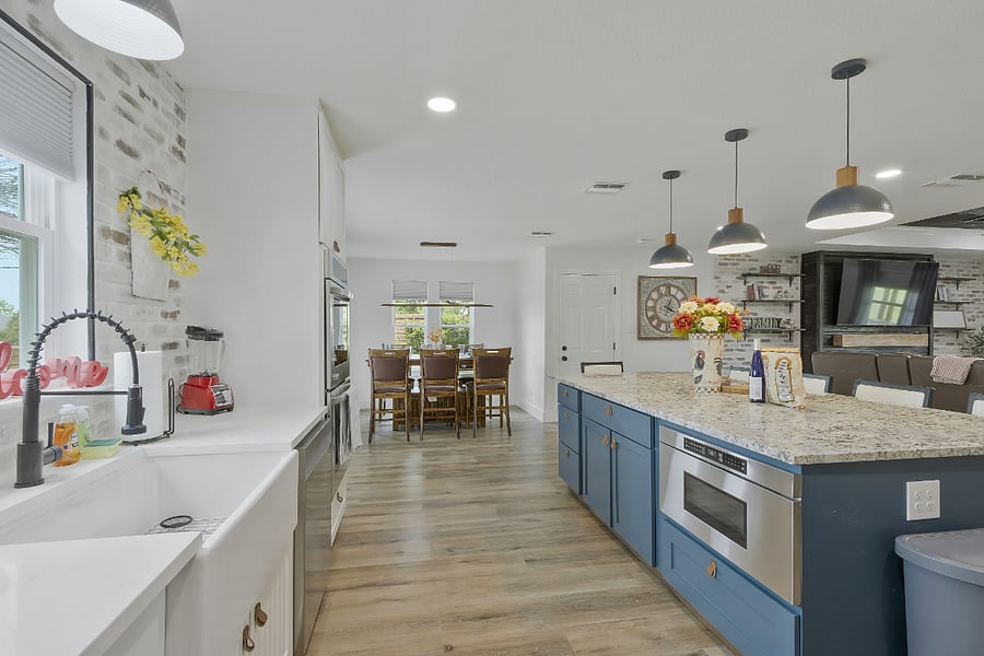 A large custom chef's kitchen with a barn door pantry, gas stove top, drawer-style microwave in the island, double oven, and farm-style sink.