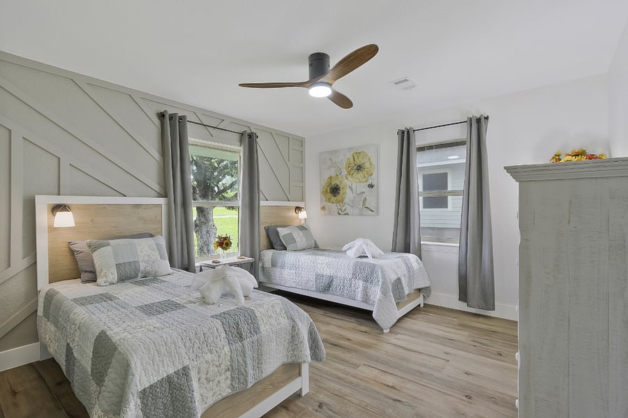 4th guest bedroom with 2 twin beds, ceiling fan, side table, side lights, and dresser with walk-in closet, in the center, front of the home.