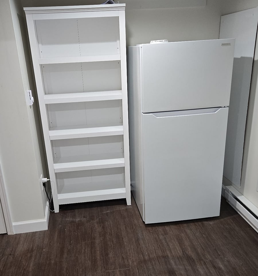 Extra shared refrigerator and shelves for more storage located in the common room outside the laundry room.