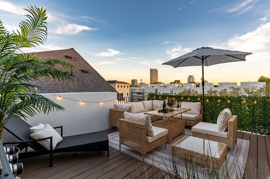 A rooftop patio with comfortable seating area, city view and ambient lighting