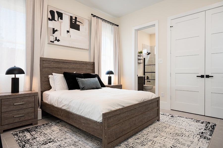 A bedroom with a queen bed, nightstands, spacious closet, full bathroom
