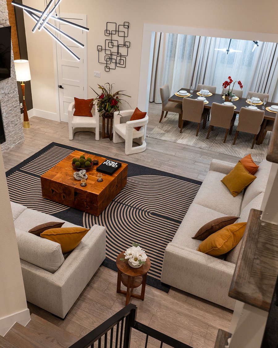 A living room with a couch, a coffee table, and a rug. The living room is open to the dining room, which has a large table and chairs. 
