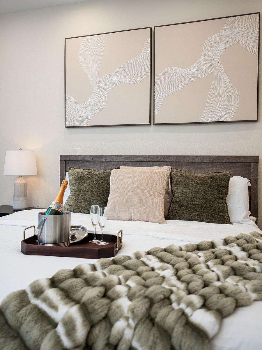 A luxurious bed with a fluffy blanket and a tray for champagne glasses and a bottle.