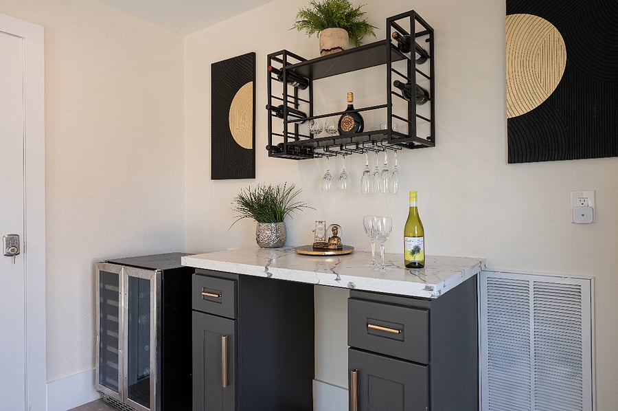 A stylish bar area with a wine rack, a mini-fridge, and a marble countertop.