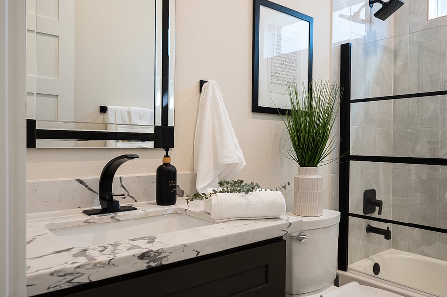 A bathroom with a sink, a mirror, and a shower.