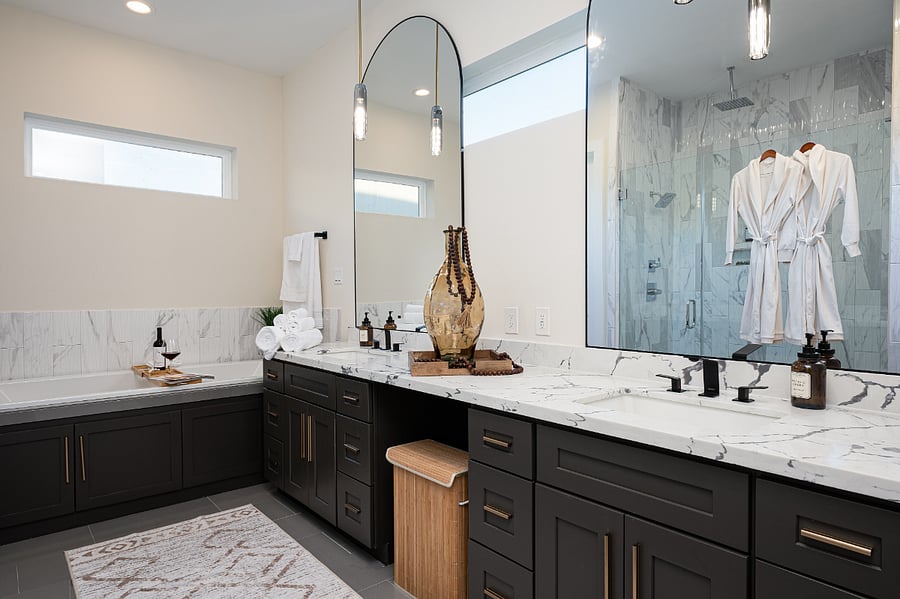 A bathroom with a double vanity, a shower, bathtub and towel warmer.