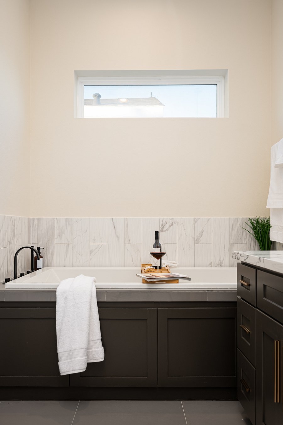 A bathroom with a bathtub, a towel, perfect for a glass of wine.