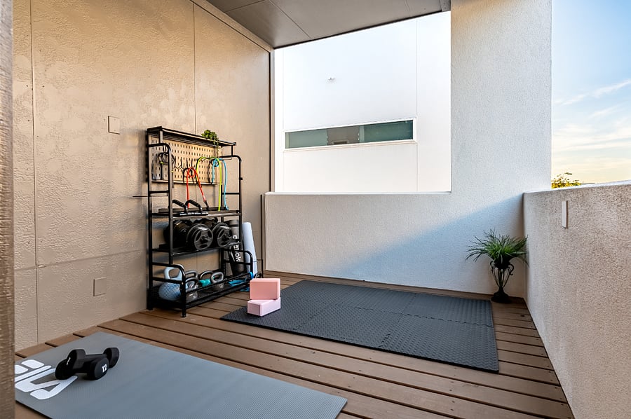 This workout room features a yoga mat, dumbbells, and plenty of space for exercise.