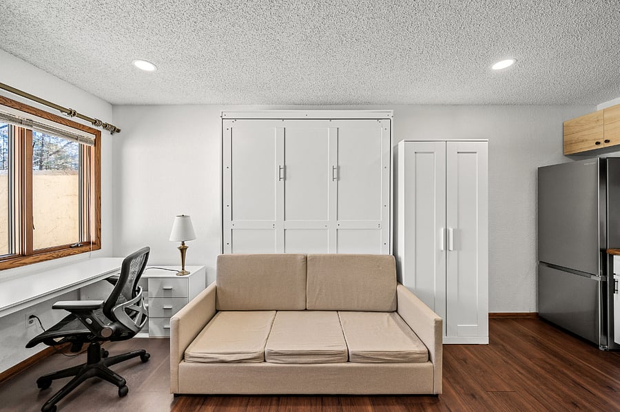 Large windows flood the space with natural light, creating a bright and productive atmosphere. They also offer a lovely view of a charming fenced-in patio, providing extra privacy.