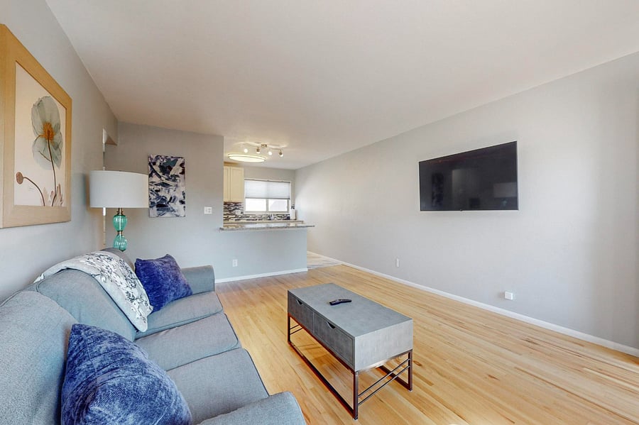 Spacious living room with wall-mounted SmartTV is open to the kitchen