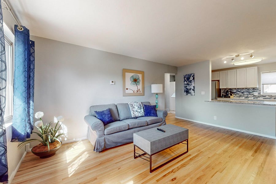 Spacious living room with wall-mounted SmartTV is open to the kitchen