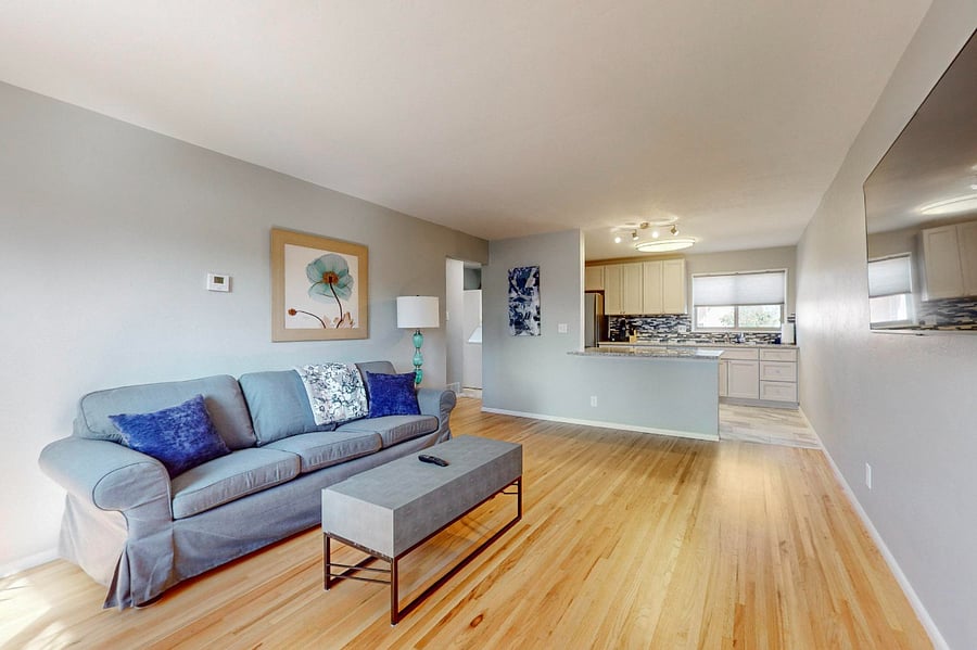 Spacious living room with wall-mounted SmartTV is open to the kitchen