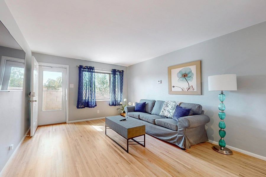 Spacious living room with wall-mounted SmartTV is open to the kitchen