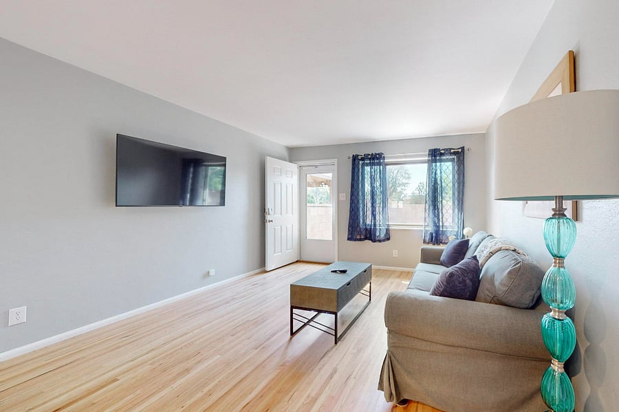 Spacious living room with wall-mounted SmartTV is open to the kitchen