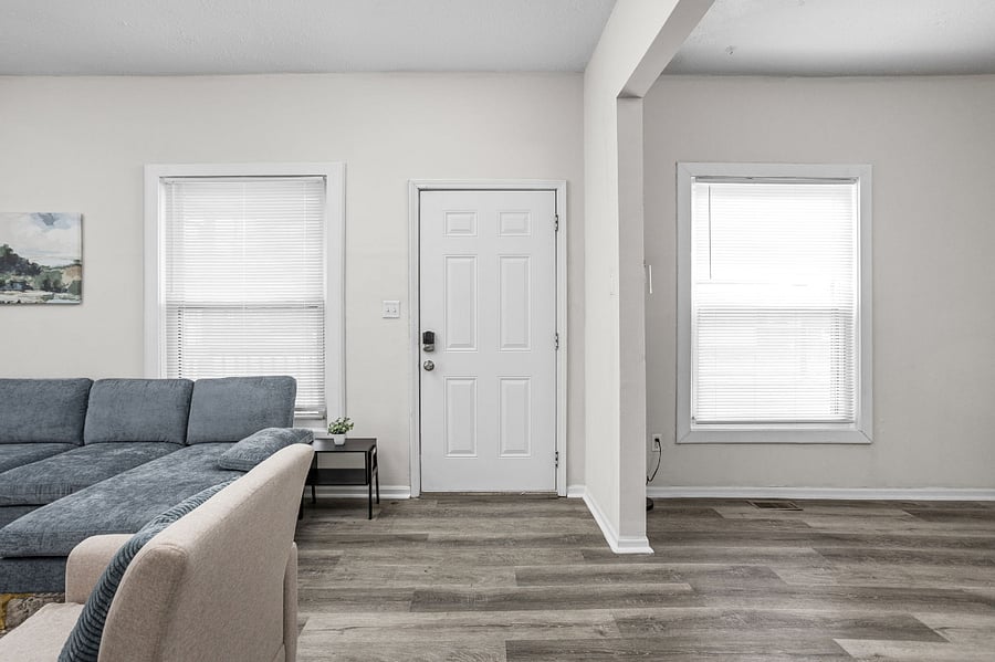 Modern living space with a cozy sectional, bright windows, and minimalist decor.