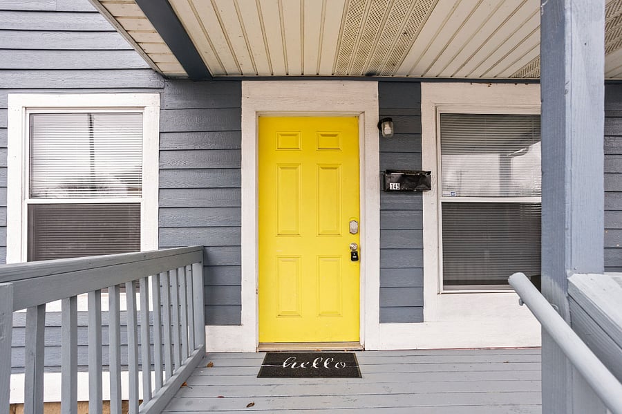Welcoming entrance with a bold yellow door and cozy front porch.