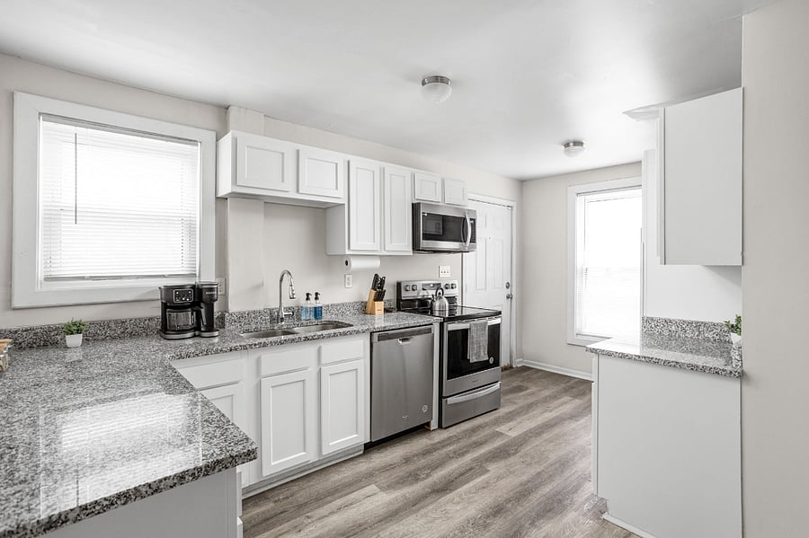 Bright and modern kitchen with sleek white cabinetry and stainless steel appliances.