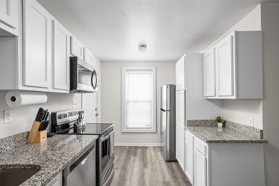 Modern and sleek kitchen featuring stainless steel appliances, white cabinetry, and stylish granite countertops.
