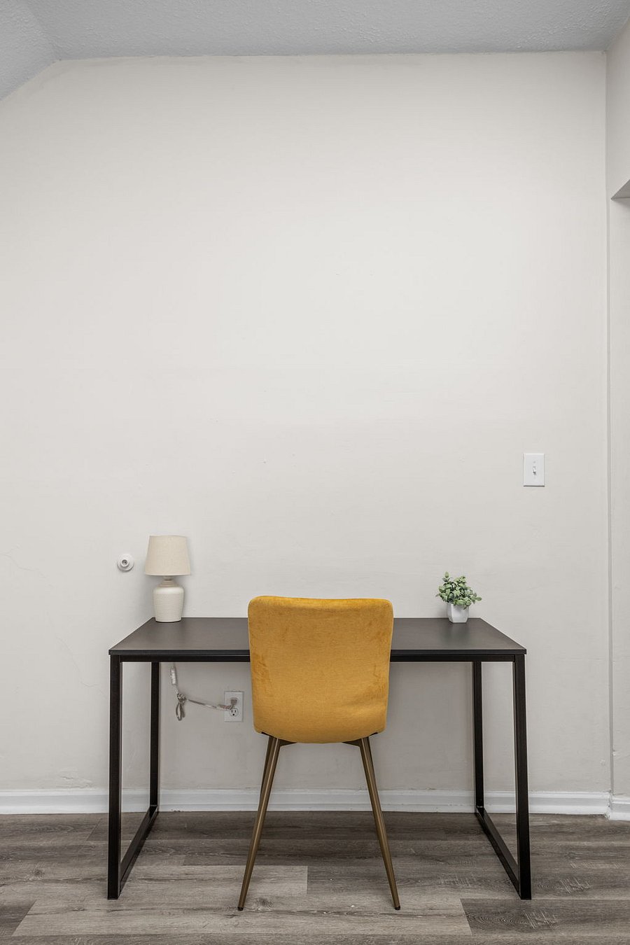Minimalist workspace with a mustard-yellow chair and sleek black desk.