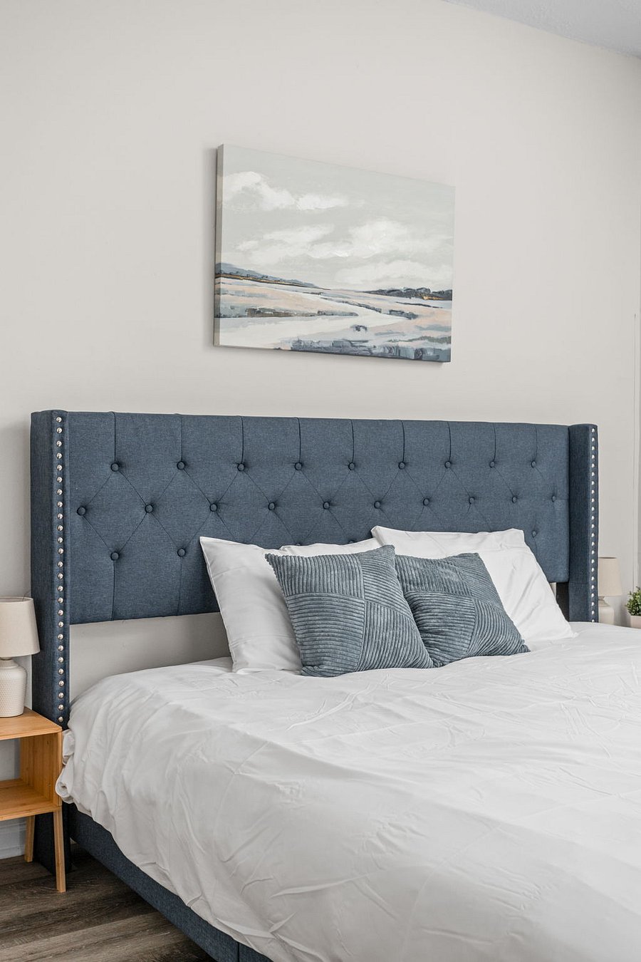 Elegant bedroom with a tufted blue headboard and stylish neutral decor.