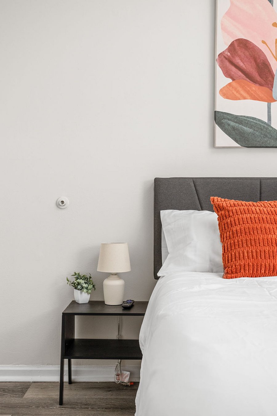 Cozy bedroom with a modern touch, featuring a bold orange accent pillow.